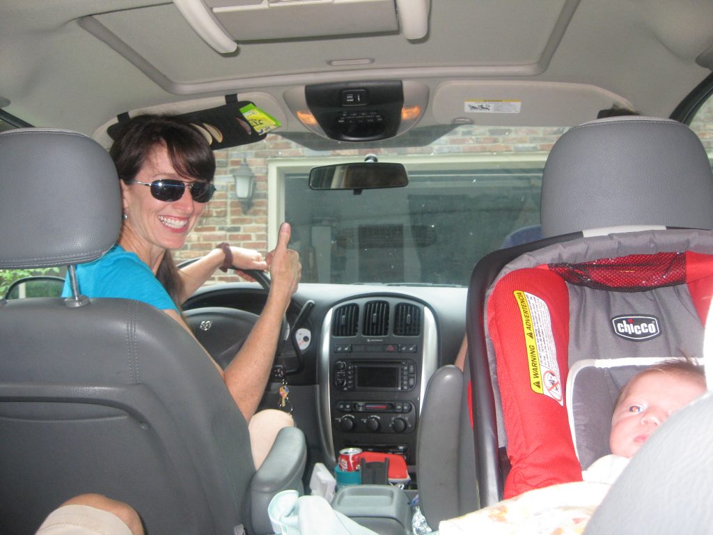 Laurel thumbs up in minivan with baby Brynn 